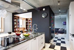 Kitchen counter with granite worksurface in front of office in square installation with black-painted walls