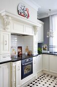 Cooker and integrated cupboards in white mantel hood in country-house kitchen