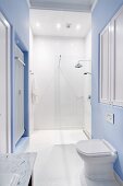 Stand-WC vor hellblau getönter Wand, vor bodenebenem Duschbereich in Weiß