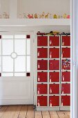 Toy cars on top of eye-catching locker cabinet with red doors in hallway with beautiful lattice door and row of squeaky toys on roof beam