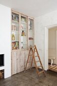 Old wooden ladder in front of fitted cupboard with doors made from wooden boards and glass