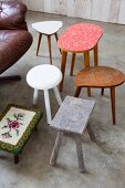 Wooden stools, 50s side table, footstool with floral, tapestry cover and leather swivel armchair on concrete floor