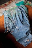 Work overalls splattered with paint draped over leather armchair