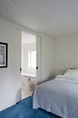 Minimalistisches Schlafzimmer mit offener Schiebetür zum Badezimmer
