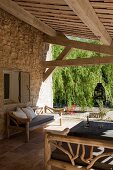 Outdoor furniture made from branches on roofed terrace adjoining Provençal stone house