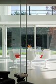 Essplatz mit Tulip Table und passenden Stühlen in weiss im Klassikerstil auf weißem Kunstharzboden in zeitgenössischer Architektur