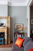 Dark grey couch with orange, silk scatter cushions in traditional living room with grey-painted wall