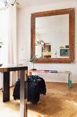 Table and bench made from book bindings and large, framed mirror on wall