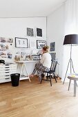 Woman sitting at desk and standard lamp wit black lampshade in home office