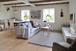 Essplatz und Sitzbereich mit Sofa im offenen Wohnraum mit Holzwänden und sichtbaren Deckenbalken