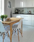 Elegant, white kitchen counter, vintage kitchen table and Eames chairs in renovated country house