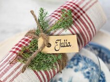 Rolled napkin decorated with name tag and festive sprig of green