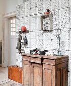 Antique, rustic cabinet against foyer wall clad in moulded tiles