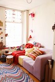 Lounge area in shades of red and pink with tree-stump table, woven rug, knick-knacks, Indian souvenirs and cuckoo clock