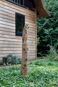 Owl sculpture carved from tree trunk in front of woodland house
