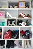 Collection of shoes, bags and framed, mounted butterfly on open-fronted shelves