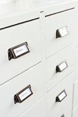 Labelled drawer handles on white-painted, vintage chest of drawers