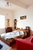 Red leather couch and patchwork bedspread on double bed in retro bedroom