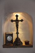 Kleine Wandnische beleuchtet, mit Devotionalie und Tischstanduhr