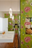 Sink on mirrored wall and floor-mounted taps in designer bathroom with floral wallpaper