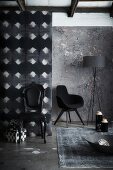 Corner furnished in shades of grey and black; black, postmodern, upholstered chair and armchair in background next to standard lamp