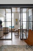 Blick durch verglaste Stahlschiebetüren in die offene Küche mit Essplatz