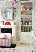 Shelves of soft toys and books in niche, floral wallpaper and pink dolls' house in front of disused fireplace
