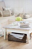 White, vintage coffee table and old, wooden crate in front of corner bench with various scatter cushions