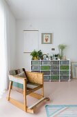 Rocking chair made from multicoloured wooden boards and sideboard holding vintage metal crates against wall in modern interior