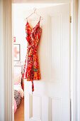 Colourful summer dress hanging on half-open bedroom door