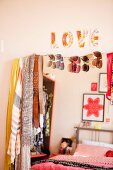 Tücher, Gürtel und Sonnenbrillen an einem Spiegel mit der Reflektion eines rot dekorierten Bettes