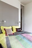 Double bed below and reading lamps against grey wall