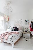 Grafisch gemusterte Bettwäsche und Kissen auf femininem Bett, kugelförmige Pendelleuchte in romantischem Schlafzimmer