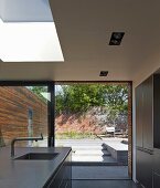 Point 7, Winchester, United Kingdom. Architect: Dan Brill Architects, 2014. Skylight above kitchen island and view of sunny terrace through glass sliding doors