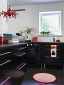 Modern laundry room with black base units, stainless steel strip handles, round rug and black tiled floor