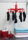 Gestapelte Handtücher unter roter, aufgehängter Wäschespinne mit Socken