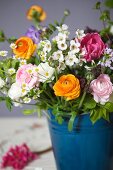 Spring bouquet of ranunculus, tulips and apple blossom in blue metal container