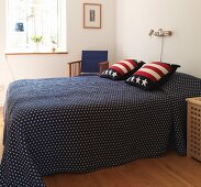 Blaue Tagesdecke und Stars and Stripes Kissen auf Doppelbett in skandinavischem Schlafzimmer