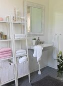 White shelves of towels and laundry baskets next to sink in romantic bathroom