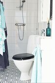 Toilet with black lid in modern bathroom with black and white ornamental floor tiles