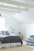 Doppelbett und Kissenstapel vor Einbauschrank in holzverkleidetem Dachzimmer
