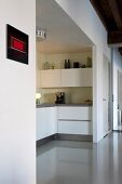 White, U-shaped, fitted kitchen in niche and glossy, grey resin floor