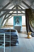 Minimalist bedroom area and bathroom in open-plan, rustic attic with exposed wooden structure