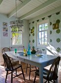 Wooden chairs around painted table in rustic dining room with white wooden ceiling