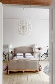 Double bed flanked by designer lamps on bedside cabinets and bicycles