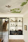 Exhibition pieces on custom shelving in elegant interior with ceiling mural