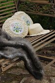 Sun hat, two old-fashioned embroidered cushions and fur blanket on antique garden swing