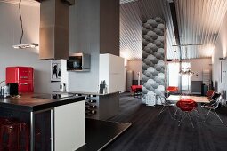 Modern kitchen area with extractor hood above free-standing counter and dining area in renovated loft apartment