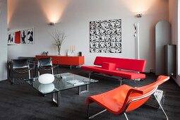 Elegante Lounge mit Sitzmöbeln im Stilmix und in kräftigen Farbtönen, im Hintergrund Wandbeleuchtung in loftartigem Wohnraum
