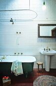 Vintage-style bathtub next to pedestal sink against white-tiled wall; historical ambiance